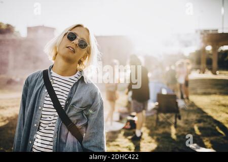 Portrait of young confident man wearing sunglasses standing in music festival Stock Photo