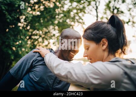 Male and female athletes exercising against trees in park Stock Photo