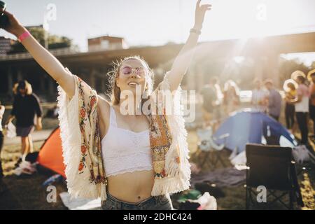 Happy young woman with arms raised enjoying at music event during summer Stock Photo