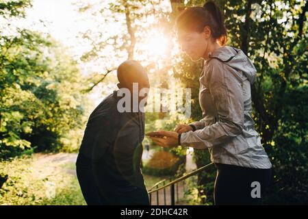 Young female athlete showing mobile phone to sportsman while standing in park Stock Photo