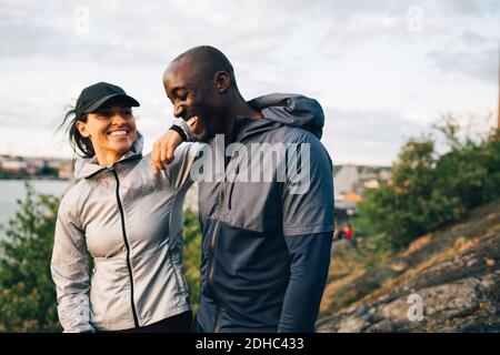Smiling male and female athlete standing on hill against sky Stock Photo