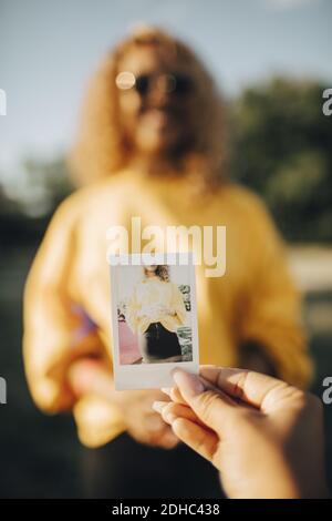 Cropped image of woman holding photograph against woman Stock Photo
