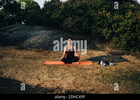 Full length of young woman practicing yoga on field in park Stock Photo
