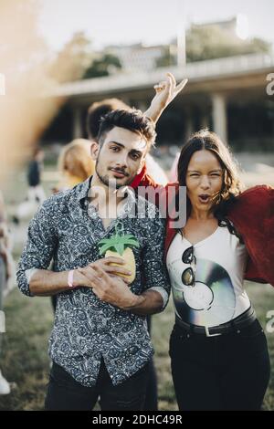 Portrait of woman dancing while standing with friend having drink at concert Stock Photo