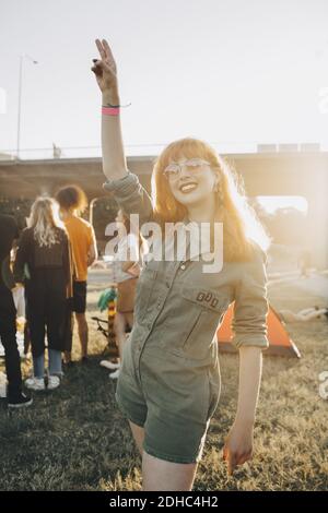 Happy young woman gesturing while standing on lawn Stock Photo