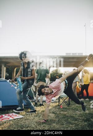 Young friends dancing on grassy field against sky Stock Photo