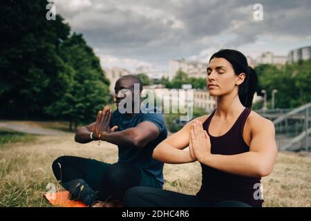 Multi-ethnic friends practicing yoga on field in city Stock Photo