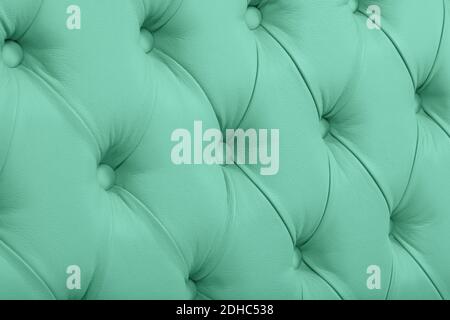 Close up background texture of pastel teal green capitone genuine leather, retro Chesterfield style soft tufted furniture upholstery with deep diamond Stock Photo