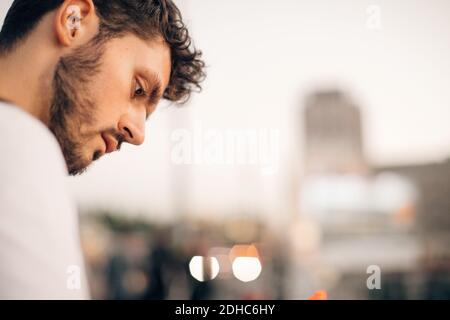 Thoughtful young man looking down during city break Stock Photo