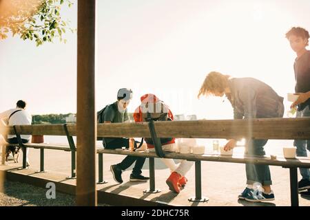 Friends with take out food on promenade in city during sunny day Stock Photo