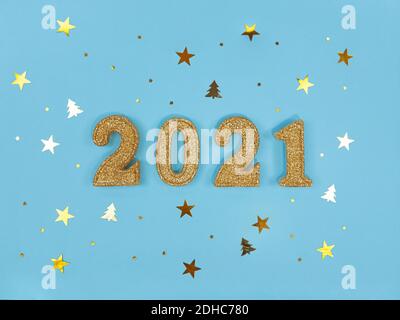 Greeting card of New Year 2021. Golden glittered figures and confetti on blue background. Stock Photo