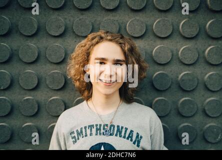 Portrait of smiling young man standing against wall Stock Photo