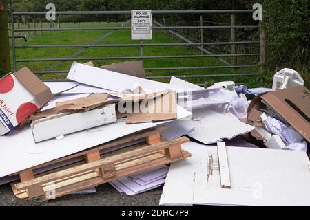 Illegal fly tipping of rubish in the countryside next to a police warning sign Stock Photo