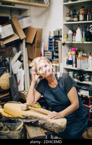 Portrait of confident female upholstery worker sitting at workbench in workshop Stock Photo