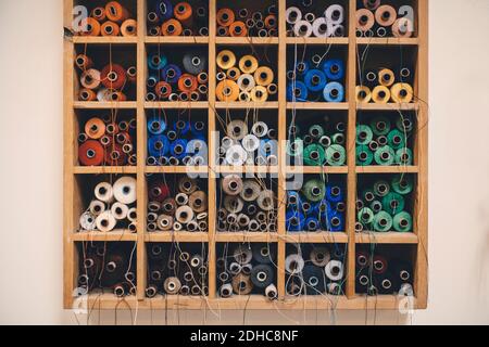 Colorful thread spools in rack at upholstery workshop Stock Photo