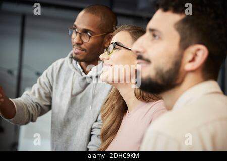Smiling male and female entrepreneurs watching presentation in creative office Stock Photo