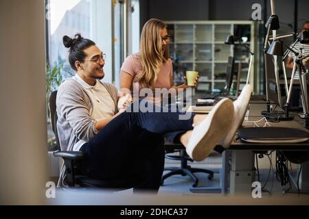 Smiling male and female entrepreneurs looking at laptop in creative office Stock Photo