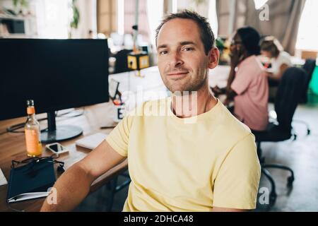 Portrait of confident businessman sitting in creative office Stock Photo