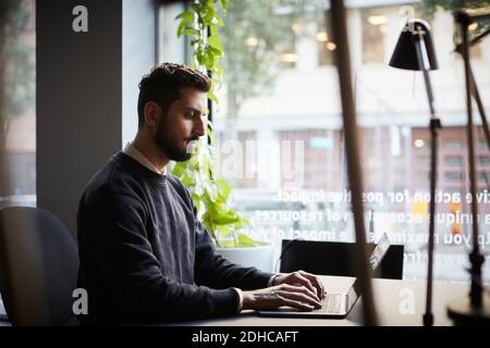 Creative businessman using laptop at desk in creative office Stock Photo