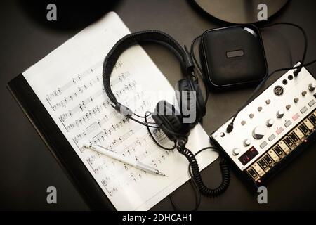 Directly above shot of headphones on sheet music with sound equipment on desk in office Stock Photo