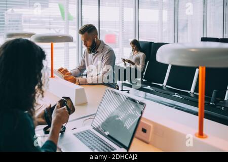 Business colleagues using technologies while sitting at airport departure area Stock Photo