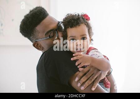 Young man kissing daughter while carrying against wall at home Stock Photo