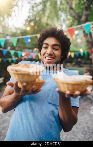 Smiling young man carrying food in bowls during garden party Stock Photo