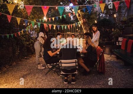 Multi-ethnic friends having dinner during garden party in backyard Stock Photo