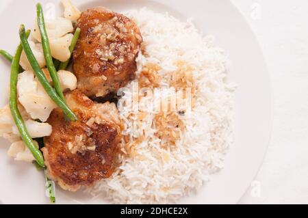 crispy fried chicken thighs with vegetables over rice in a lemon sauce Stock Photo