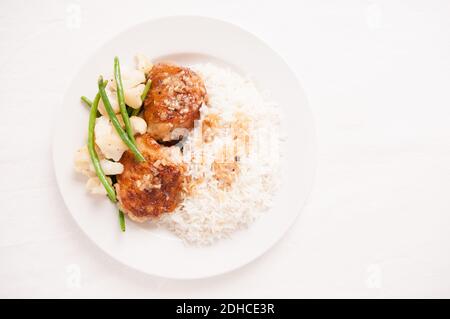 crispy fried chicken thighs with vegetables over rice in a lemon sauce Stock Photo