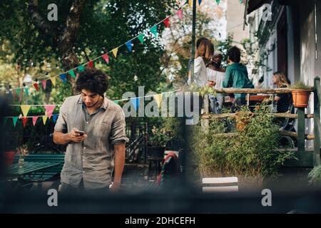 Young man using mobile phone while standing in backyard Stock Photo