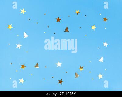 Confetti stars and trees sparkling on blue background. Stock Photo