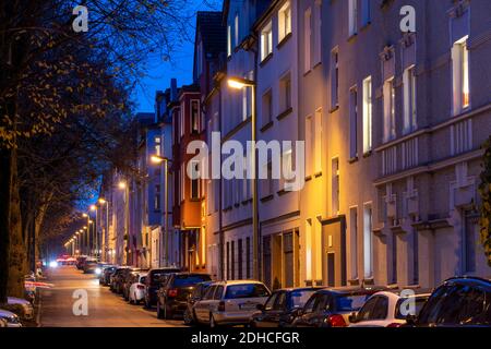 Wohnstrasse, viele Mehrfamilienhäuser in einem Wohnviertel, abends, Laternen Beleuchtung, Essen, NRW, Deutschland Stock Photo
