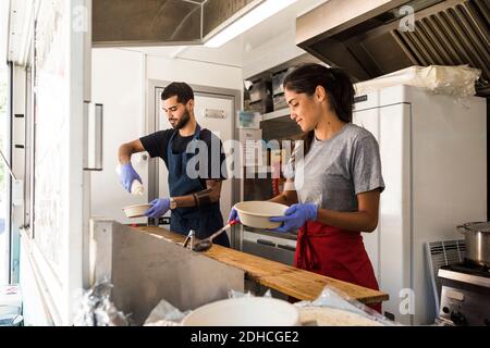 Young multi-ethnic male and female colleagues preparing food in food truck Stock Photo