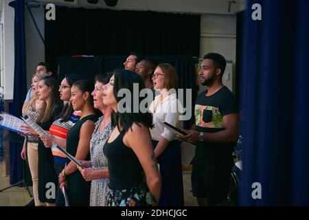 Multi-ethnic group of students singing in choir at school auditorium Stock Photo
