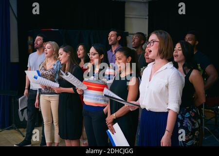 Multi-ethnic male and female students singing in choir at auditorium Stock Photo