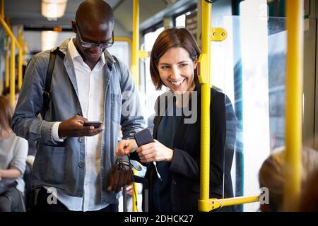 Smiling multi-ethnic commuters standing in tram Stock Photo
