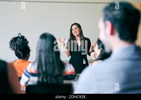 Happy teacher gesturing and explaining students in classroom Stock Photo