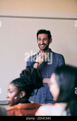 Young teacher smiling while looking at students in language class Stock Photo