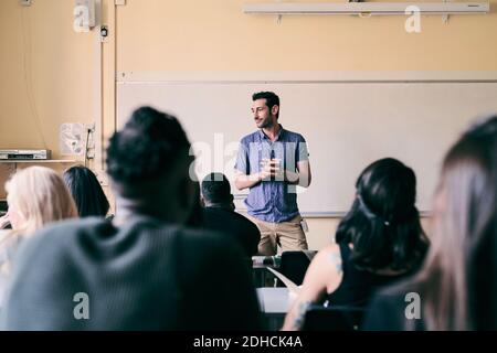 Male teacher teaching multi-ethnic students in classroom Stock Photo