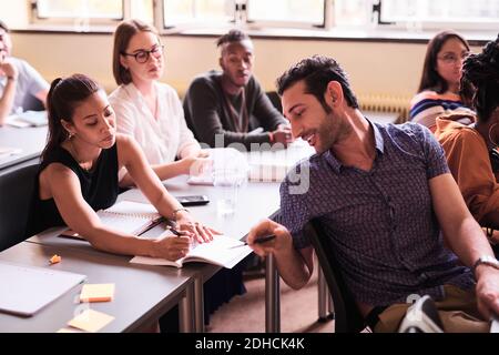 Multi-ethnic friends discussing over book in classroom Stock Photo