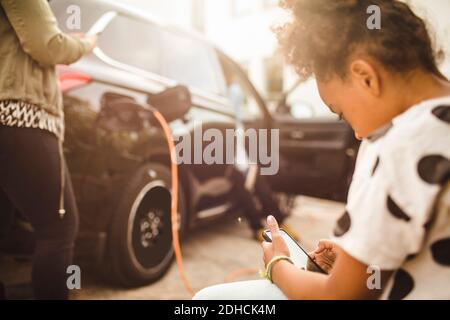 Girl using smart phone while sitting in yard Stock Photo
