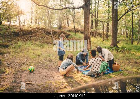 Multi-ethnic family enjoying picnic against trees at public park Stock Photo