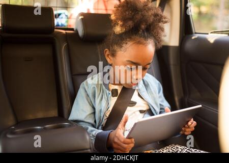 Girl using digital tablet while sitting in electric car Stock Photo