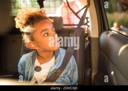 Girl looking through window while sitting in electric car Stock Photo