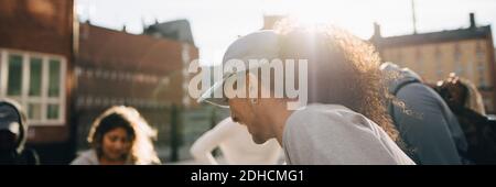 Close-up of smiling young man having fun with friends in city during sunny day Stock Photo