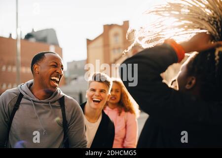 Happy male and female friends having fun in city during sunny day Stock Photo