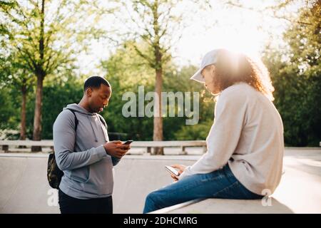 Friends using smart phone at skateboard park Stock Photo