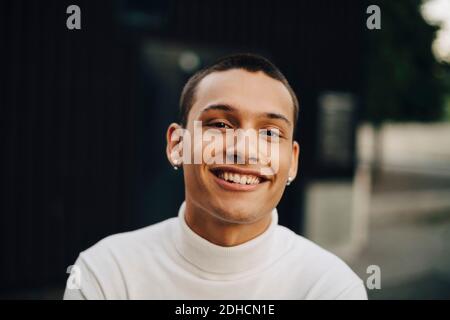 Close-up portrait of smiling young man wearing turtleneck Stock Photo