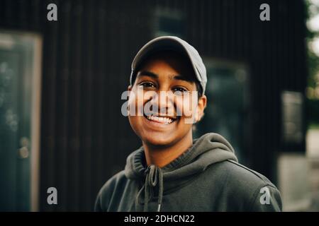 Portrait of smiling man wearing cap and hooded shirt at city Stock Photo